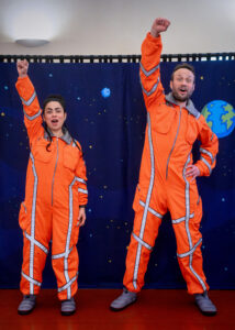 Två astronauter lyfter upp armen i luften.