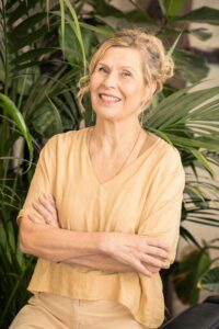 nainen keltaisessa puserossa. Hänellä on vaaleat hiukset.